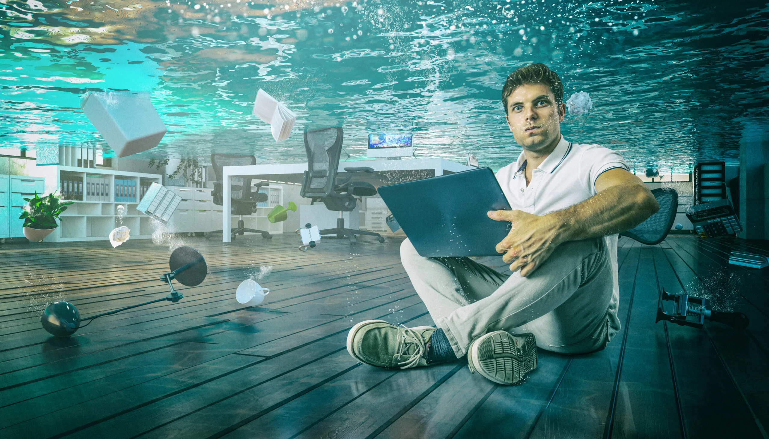 A man sitting in his flooded office, wishing he had a disaster recovery plan in place.